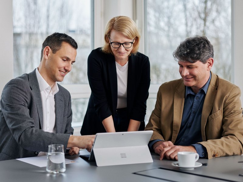 Besprechung Sabine, Emanuel u. Stefan Drei Personen welche auf einen Laptop während einer Besprechung blicken.